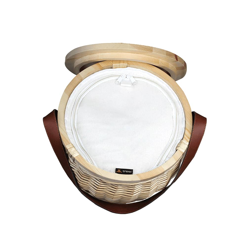 A wicker cooler basket in natural tones with a wooden lid and a brown leather strap. Contains no visible items.