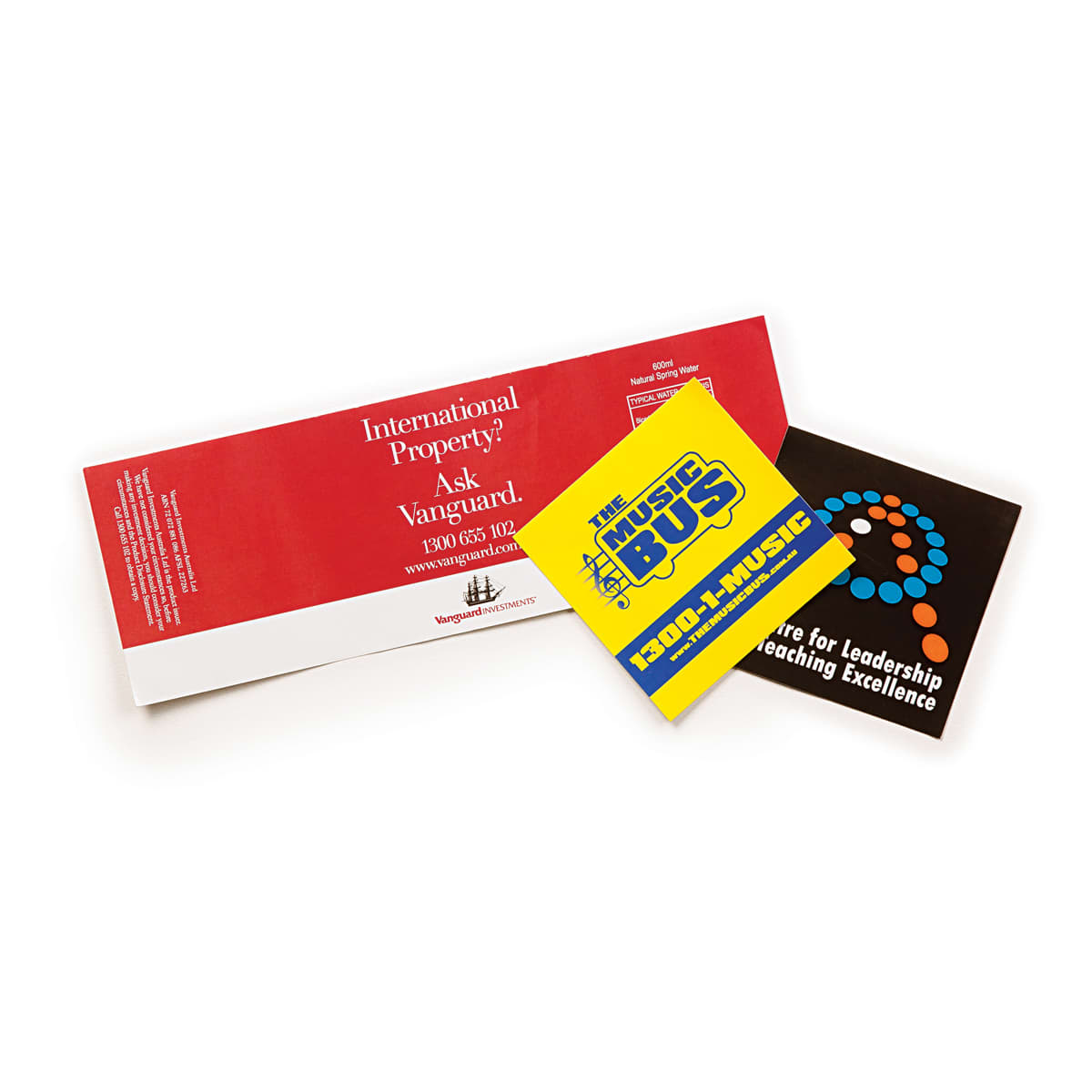 A vinyl sticker in yellow and black with a circular pattern, featuring a logo, alongside promotional materials in red and black.