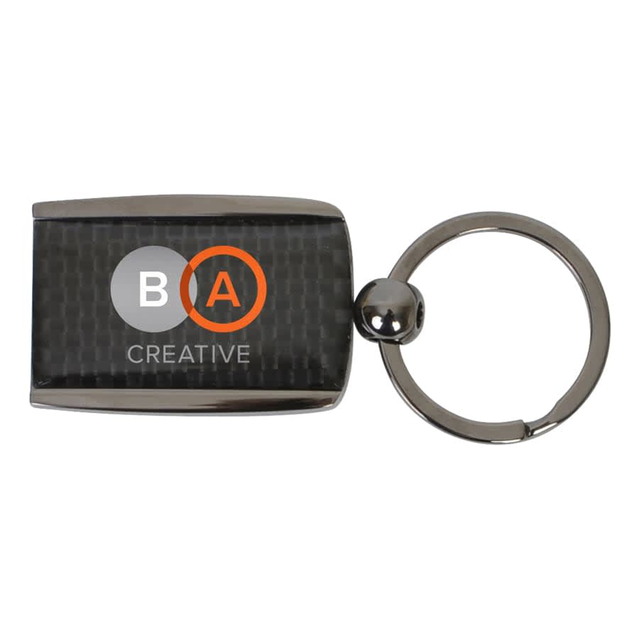 A carbon fibre keychain with a metallic finish and a round keyring attachment. Features a logo on the front.