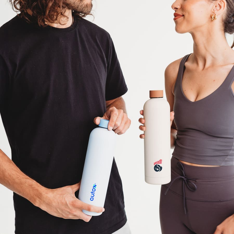 A drink bottle in light blue and another in cream, both featuring round lids, held by two people.