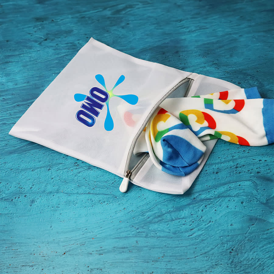 A white laundry bag with a logo, partially unzipped, revealing colourful socks inside.