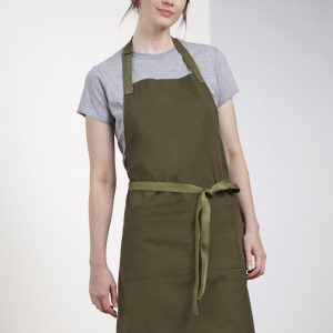An olive green apron worn by a model, featuring a tie waist and a simple design, with a logo present.
