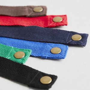 A selection of Urban Bib Straps in red, blue, green, black, and brown, featuring brass snaps.