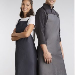 Two models wear Urban Bib Aprons in dark grey and charcoal, featuring pockets and a logo.