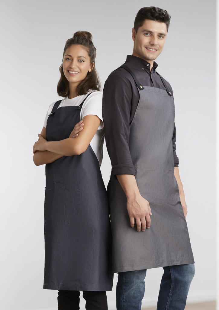 Two models wear Urban Bib Aprons in dark grey and charcoal, featuring pockets and a logo.