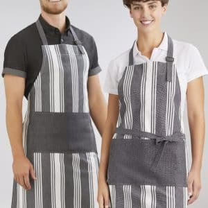 A striped grey and white apron is worn by a smiling man and woman. The aprons have a logo on them.