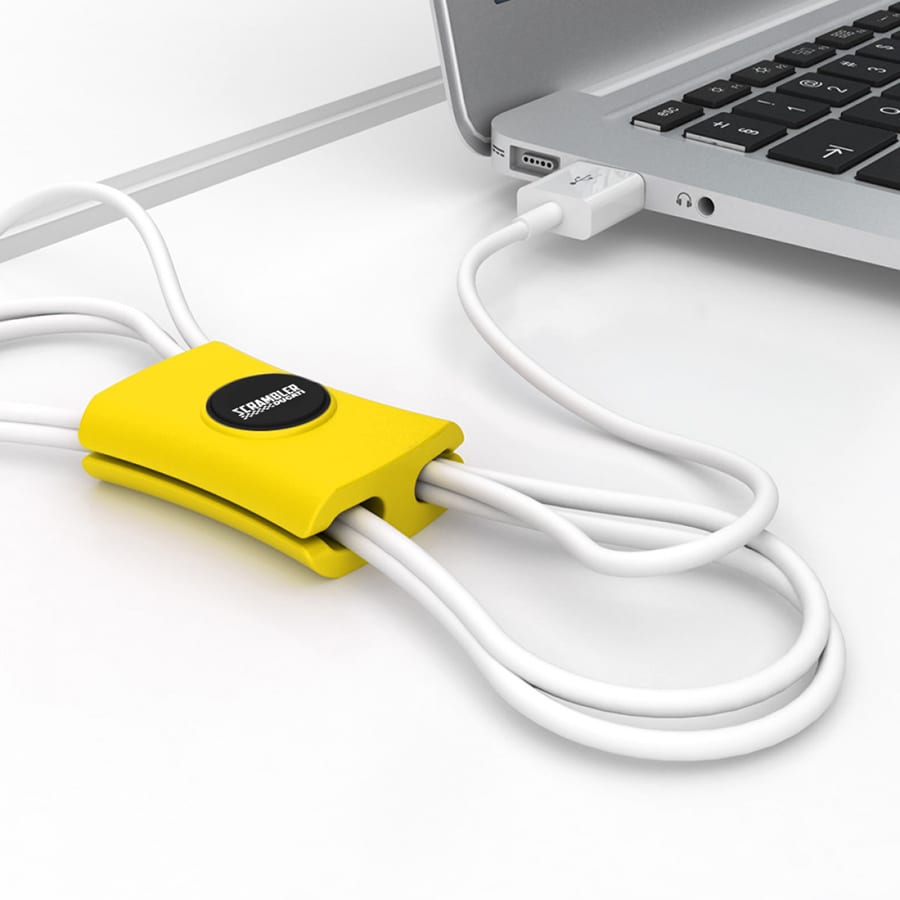 A yellow cable manager designed to tidy up multiple cords, placed next to a laptop. It has a branding logo.