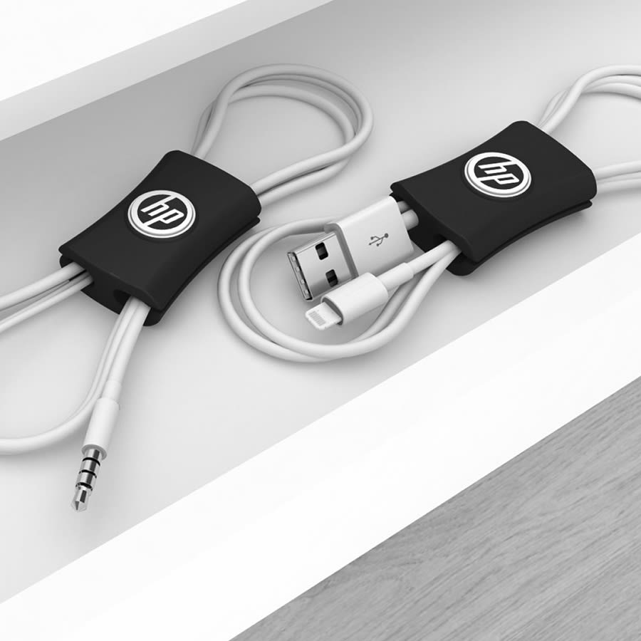 A black cable manager neatly holds multiple charging cables, featuring a logo, on a light-coloured surface.