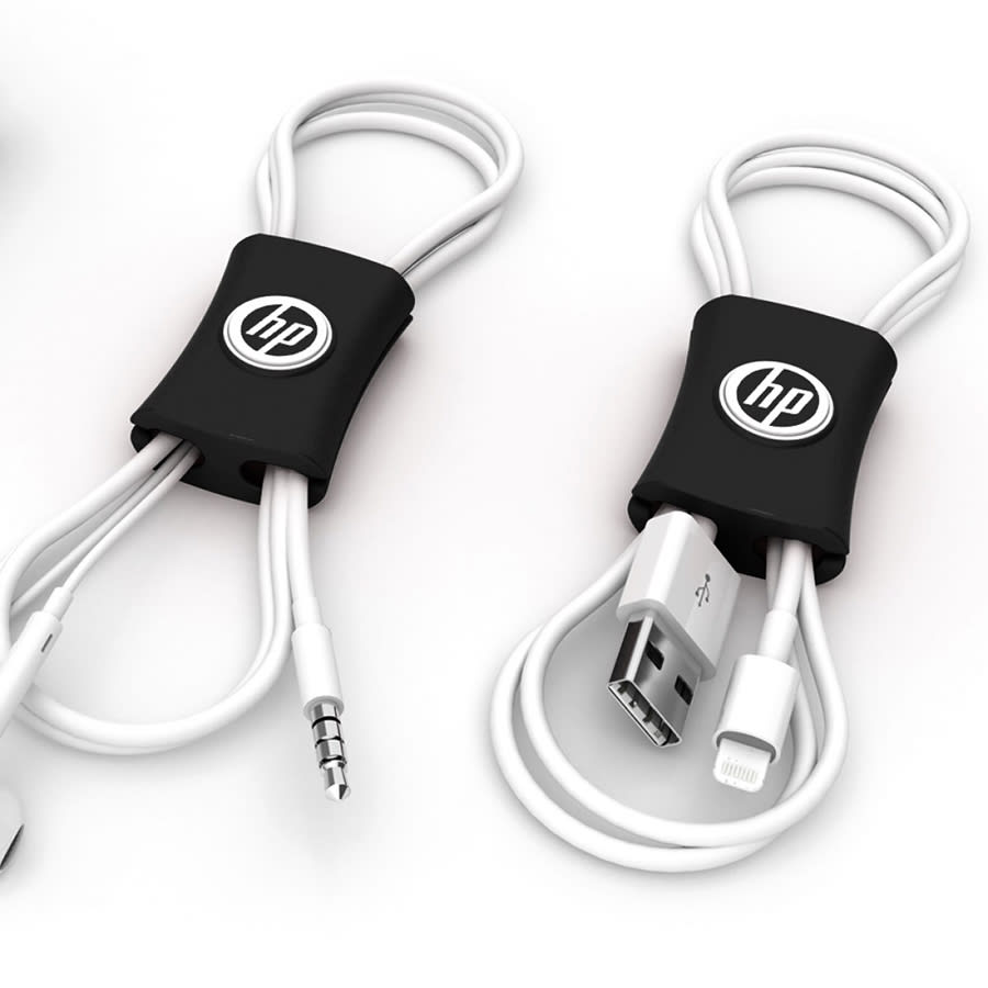 A black cable manager with a logo, designed to organise white charging and audio cables.