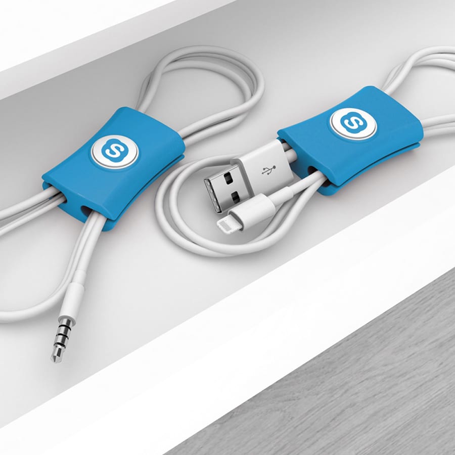 A blue cable manager designed to tidy phone cables, featuring a logo, placed on a shelf with cables neatly organized.