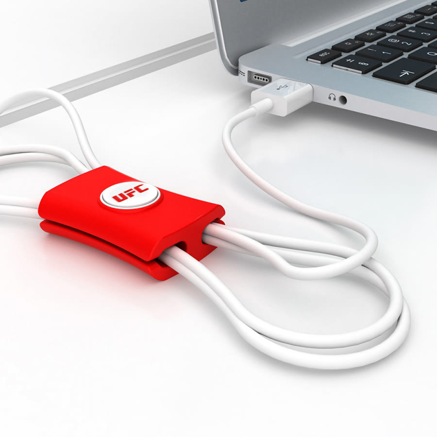 A red cable manager designed to organise and tidy cables, featuring a logo, positioned near a laptop.