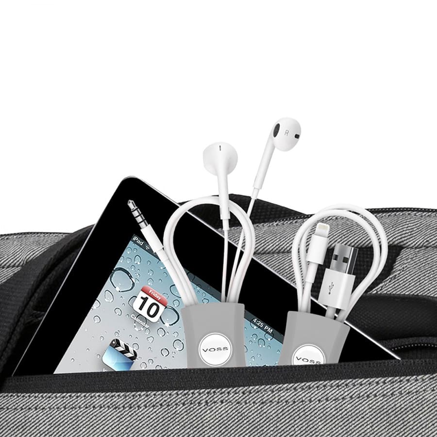 A cable manager in grey holding earbuds and charging cables, placed in a bag with a tablet visible.