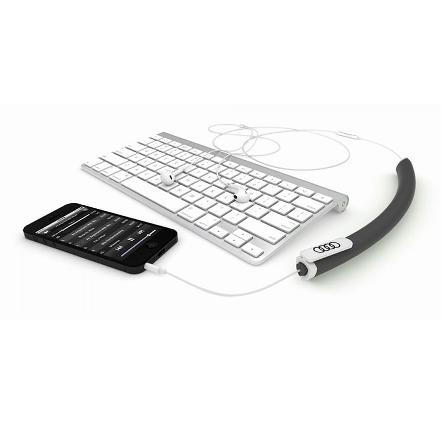 A grey earbud organizer with a white logo, alongside a smartphone and a keyboard.