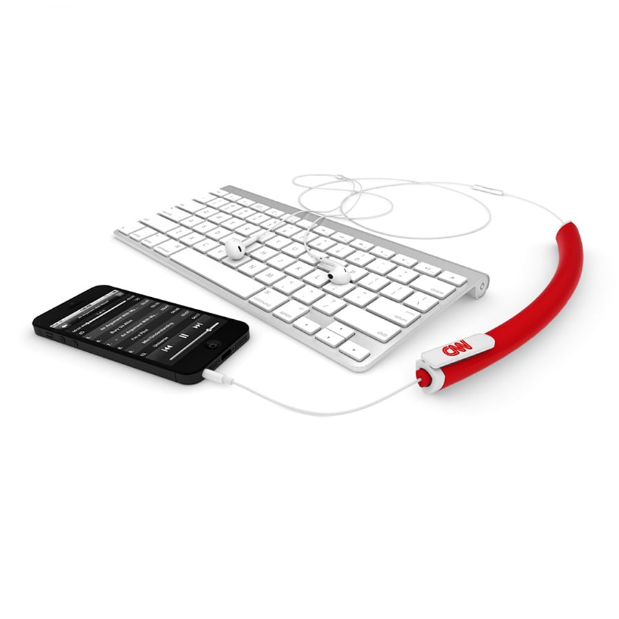 A red earbud organiser next to a smartphone and a white keyboard, efficiently managing headphone cables.