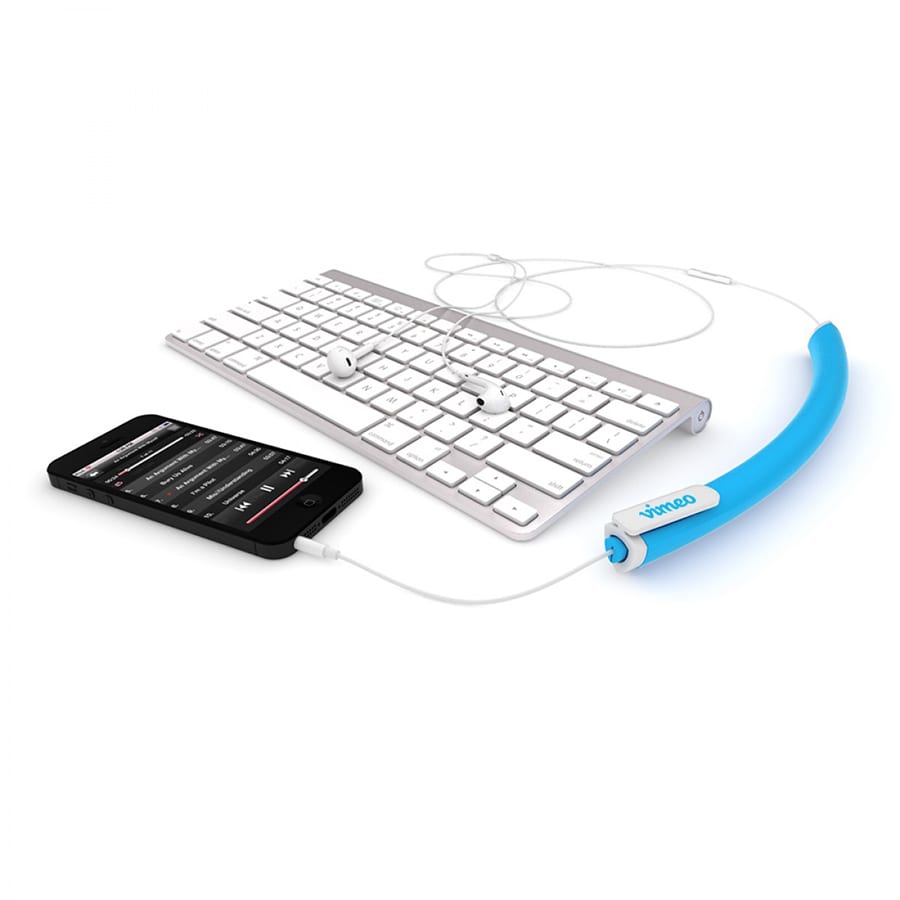 A blue earbud organiser sits next to a smartphone and white keyboard, keeping cables tidy.