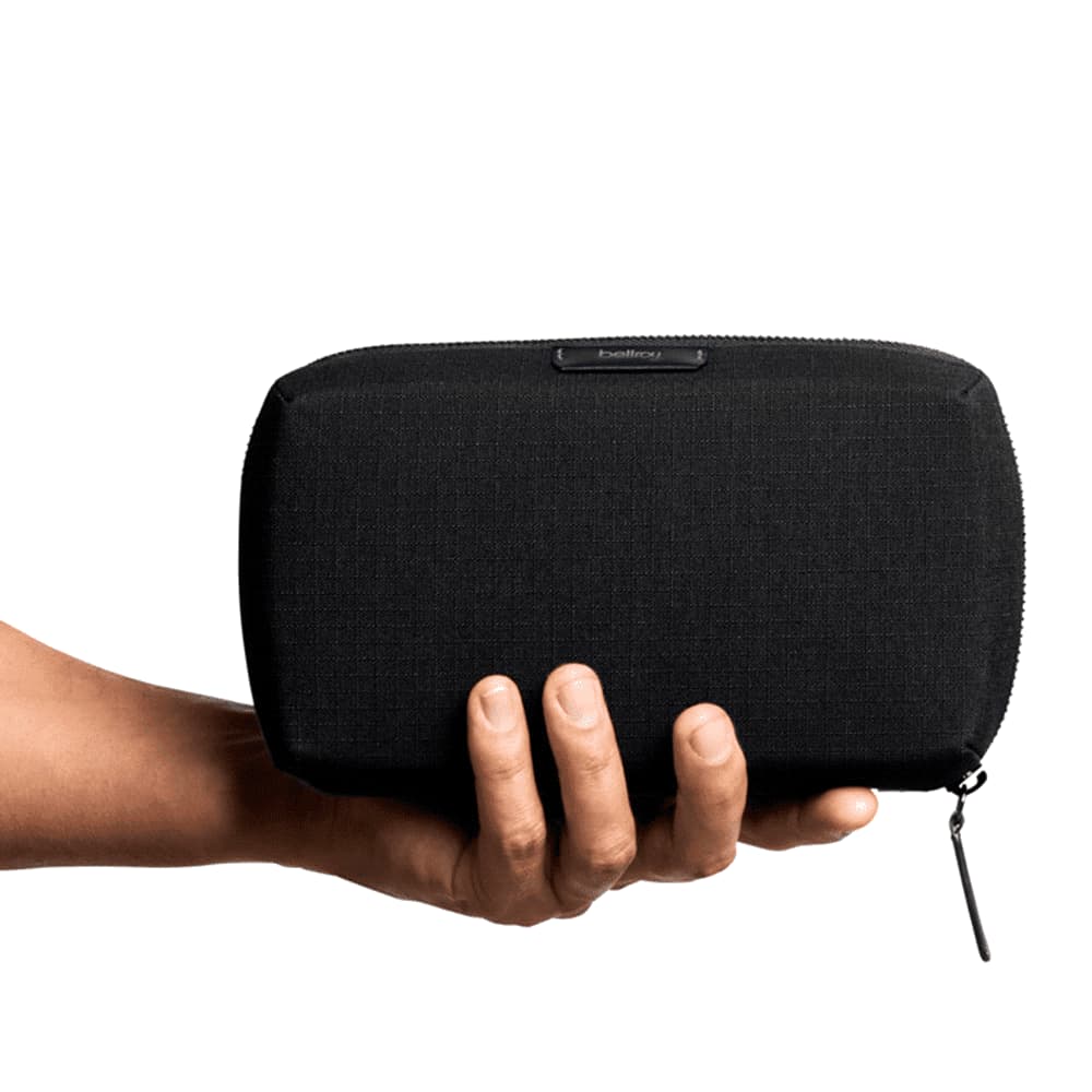 A black tech kit with a rectangular shape, featuring a textured surface and a zipper closure. It has a branding logo.