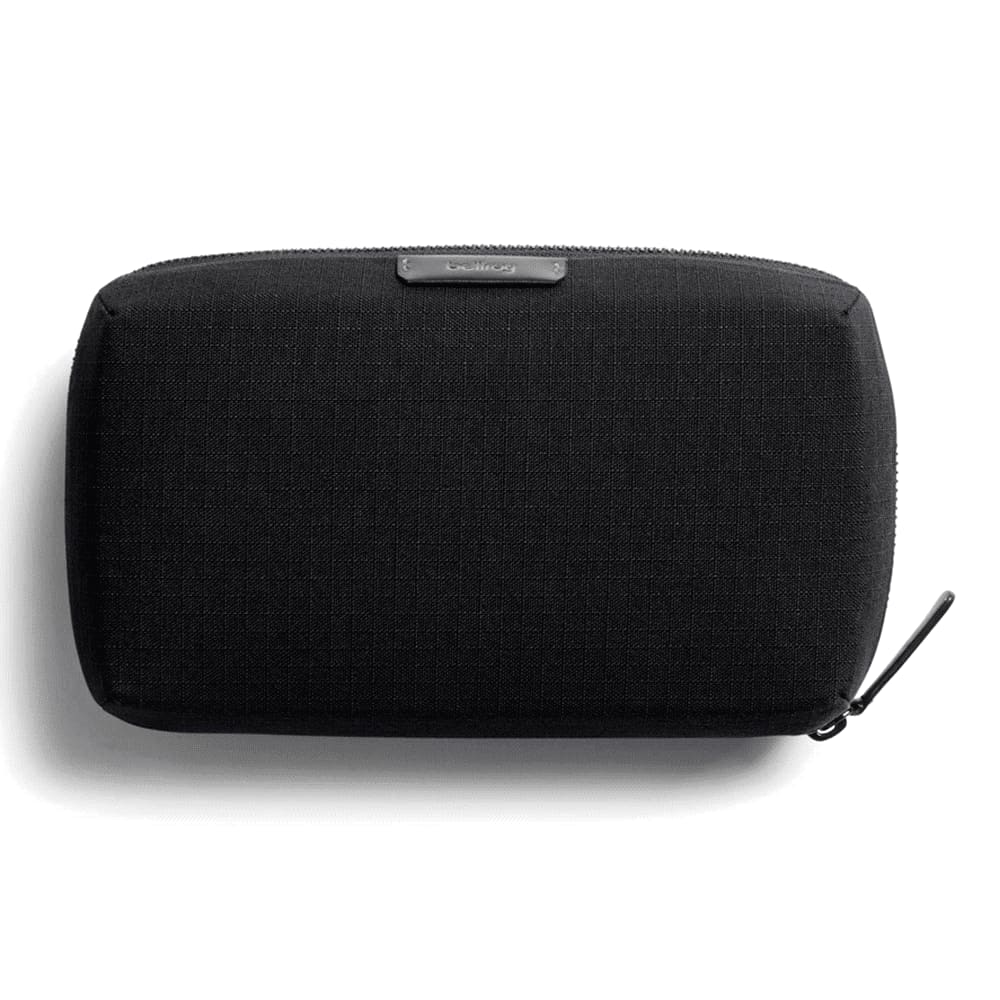 A black tech kit held in a hand, featuring a zip closure and a branding logo.
