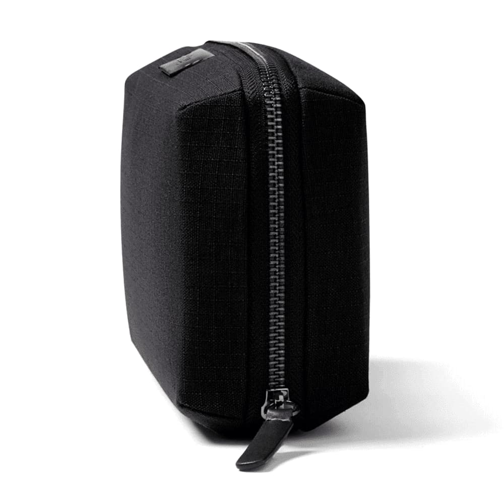 A close-up of a navy blue tech kit with a textured surface and a zip fastening, featuring a small logo.