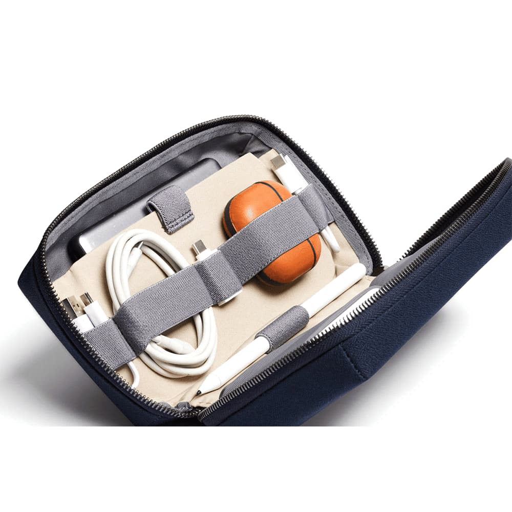 A black tech kit contains various charging cables, a power adapter, and elastic straps for organisation.