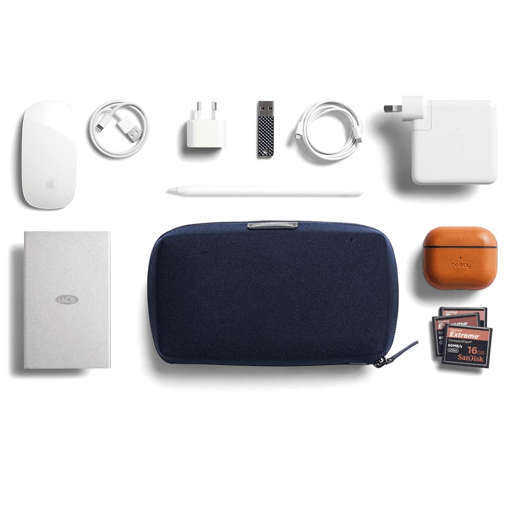 A black tech kit surrounded by a white power bank, mouse, charging cables, a stylus, AirPods, and a USB drive.