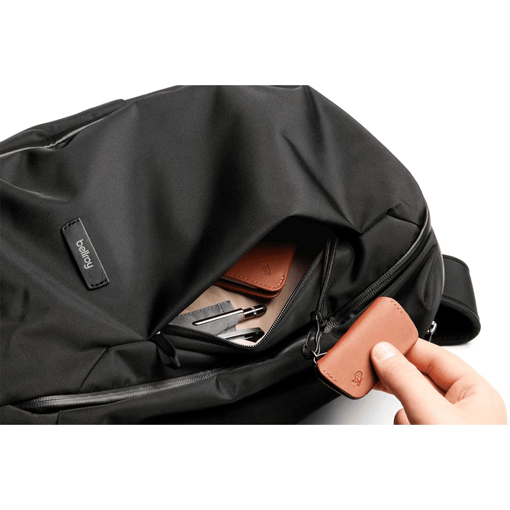 A black backpack featuring a side pocket containing an orange drink bottle. The backpack has a sleek design.