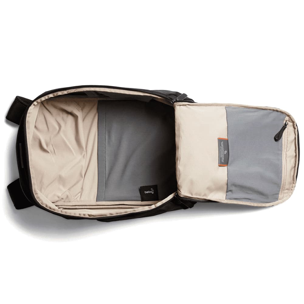A black backpack with a beige interior and a grey compartment, featuring a logo on the outside.