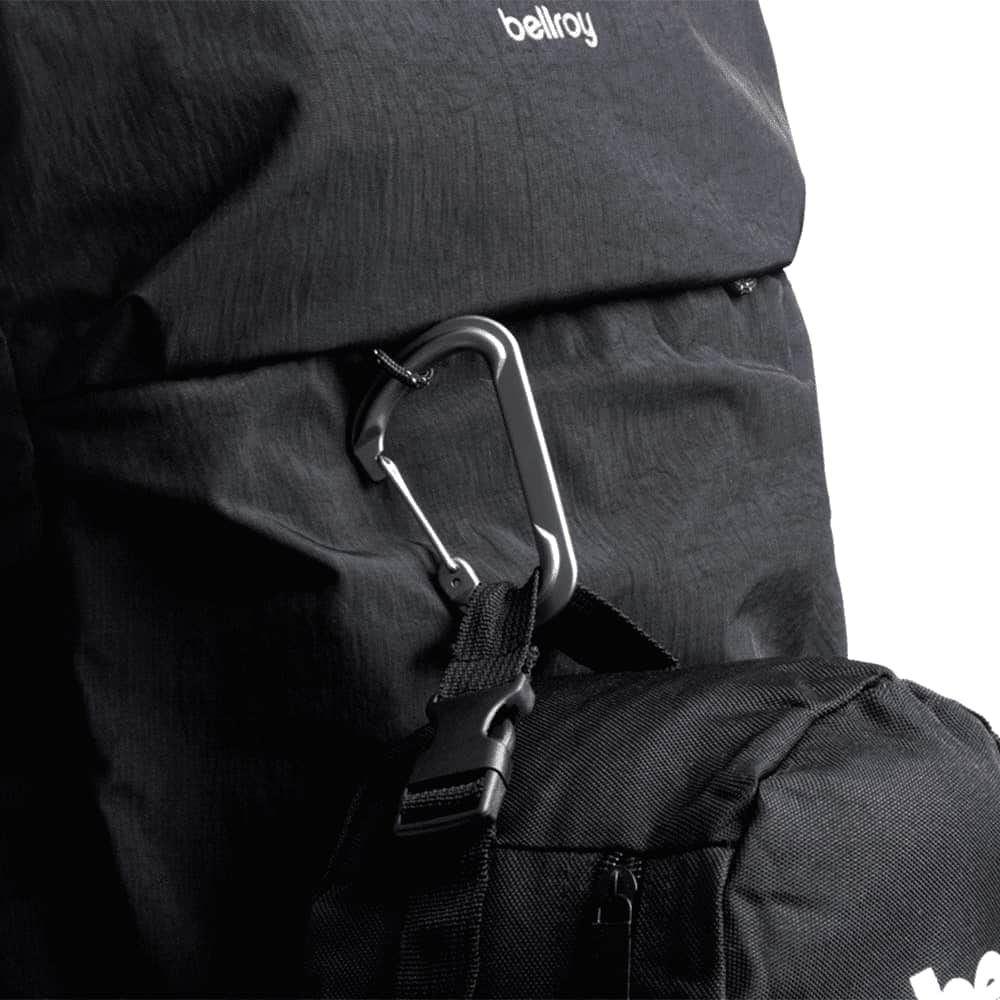 A black Bellroy Lite Travel Pack 30L backpack resting on a silver suitcase, featuring a textured panel and a logo.