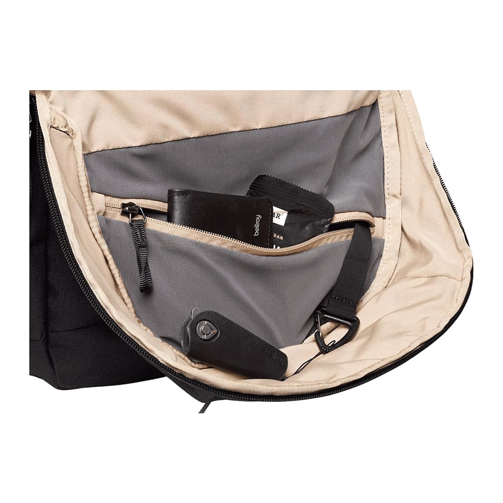 A black backpack with a zippered compartment, containing a pair of sunglasses. It features a logo on the exterior.