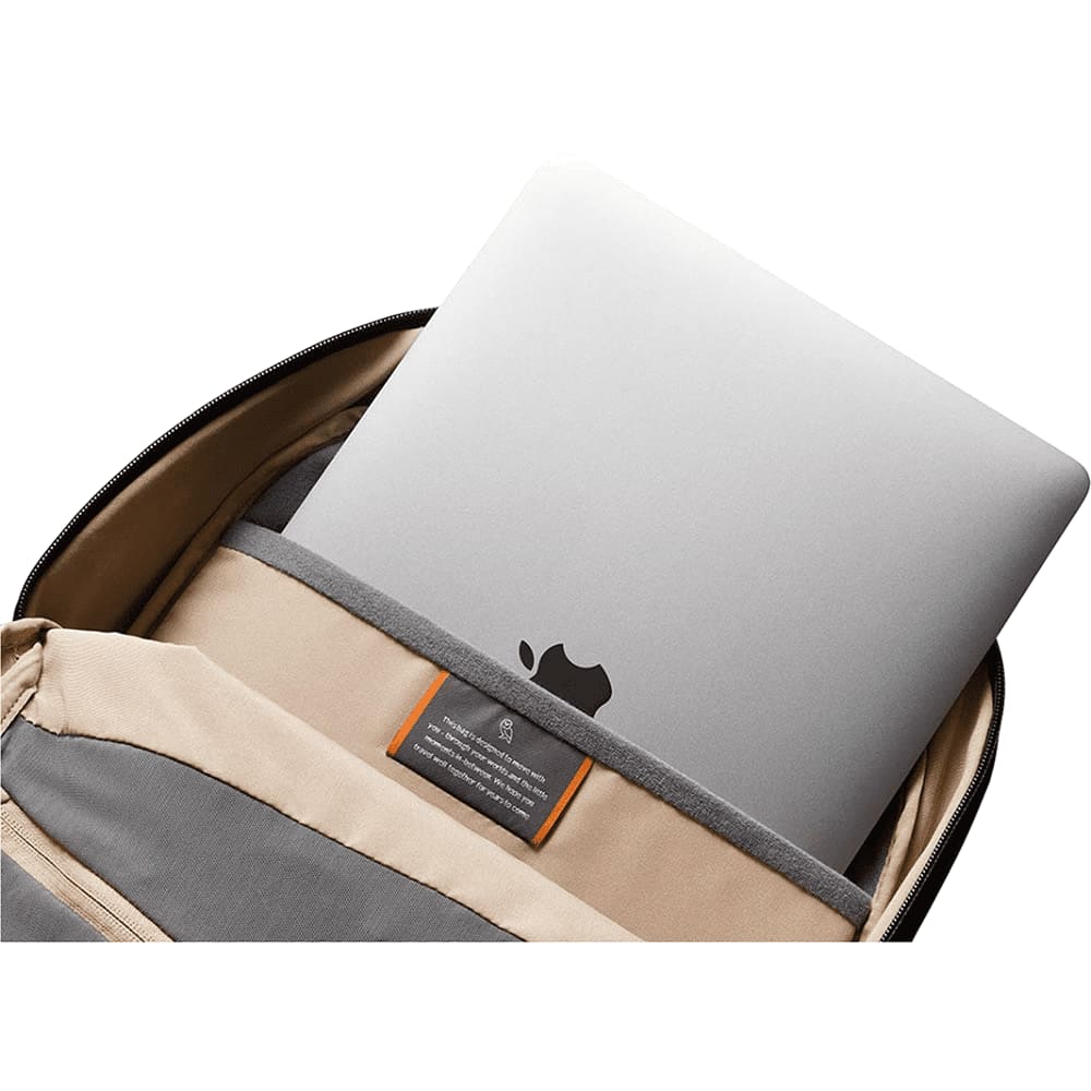 A navy Bellroy Via Backpack with a zippered compartment featuring sunglasses on top. The bag has a sleek, textured finish.