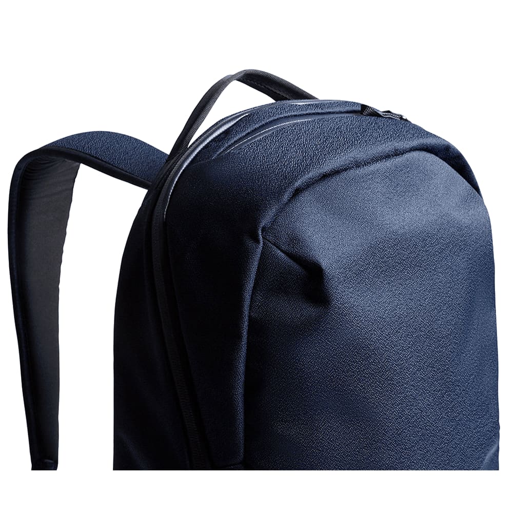 A silver laptop is nestled in the padded compartment of a tan and grey backpack, which features a logo.