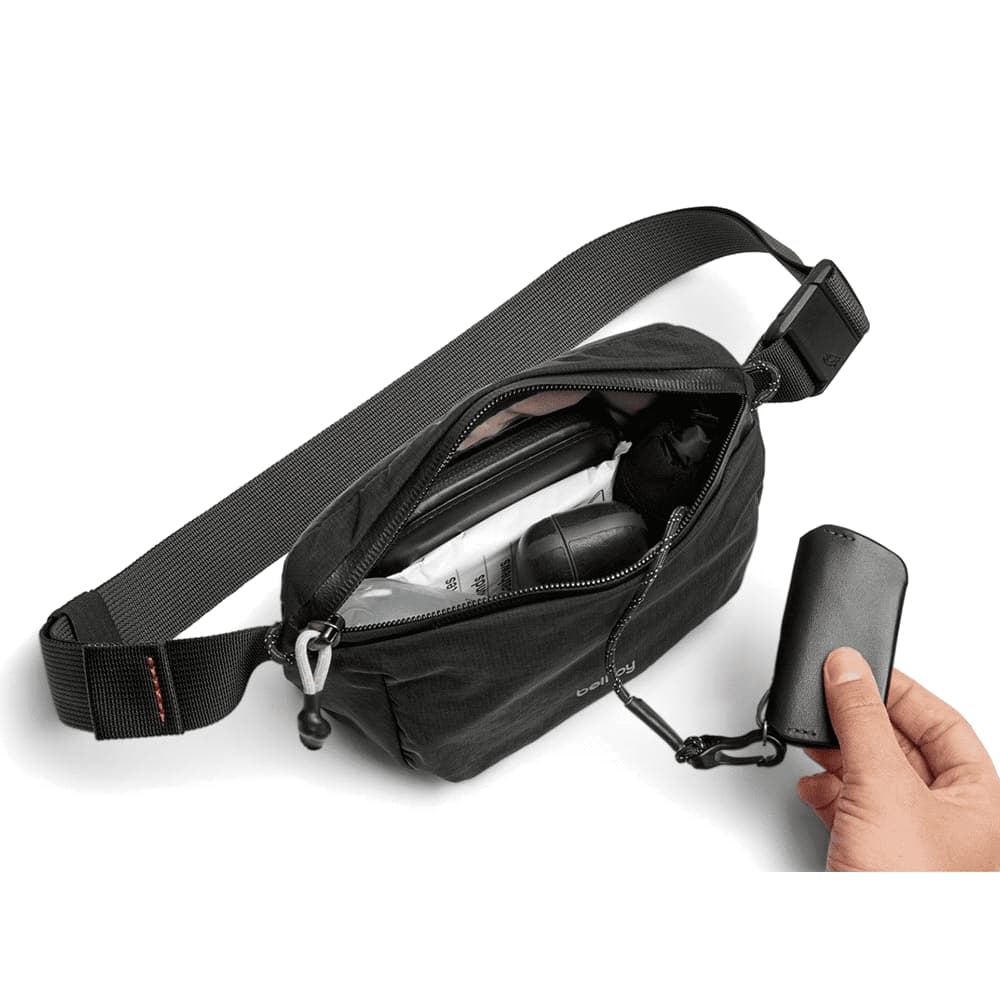 A black bum bag with a logo featured prominently, featuring an adjustable strap.