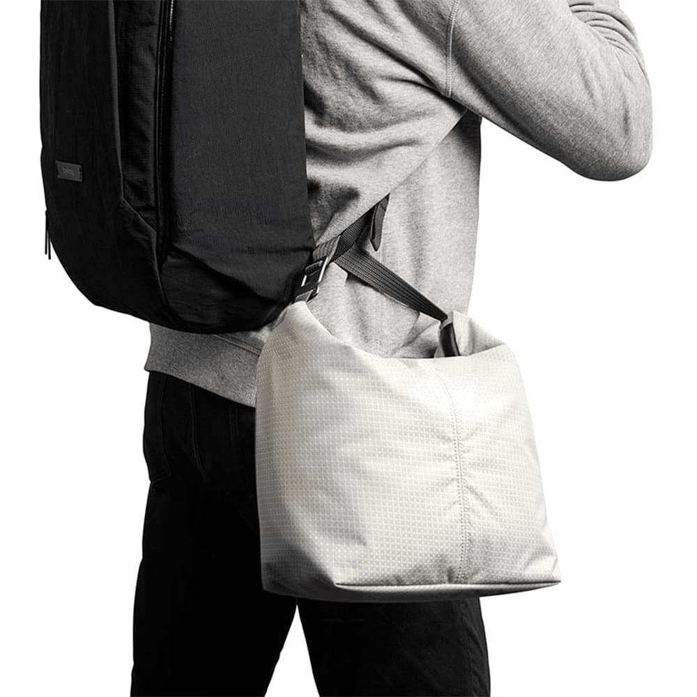 A cooler bag in light grey with a patterned surface, featuring a silver buckle and an orange branding tag.