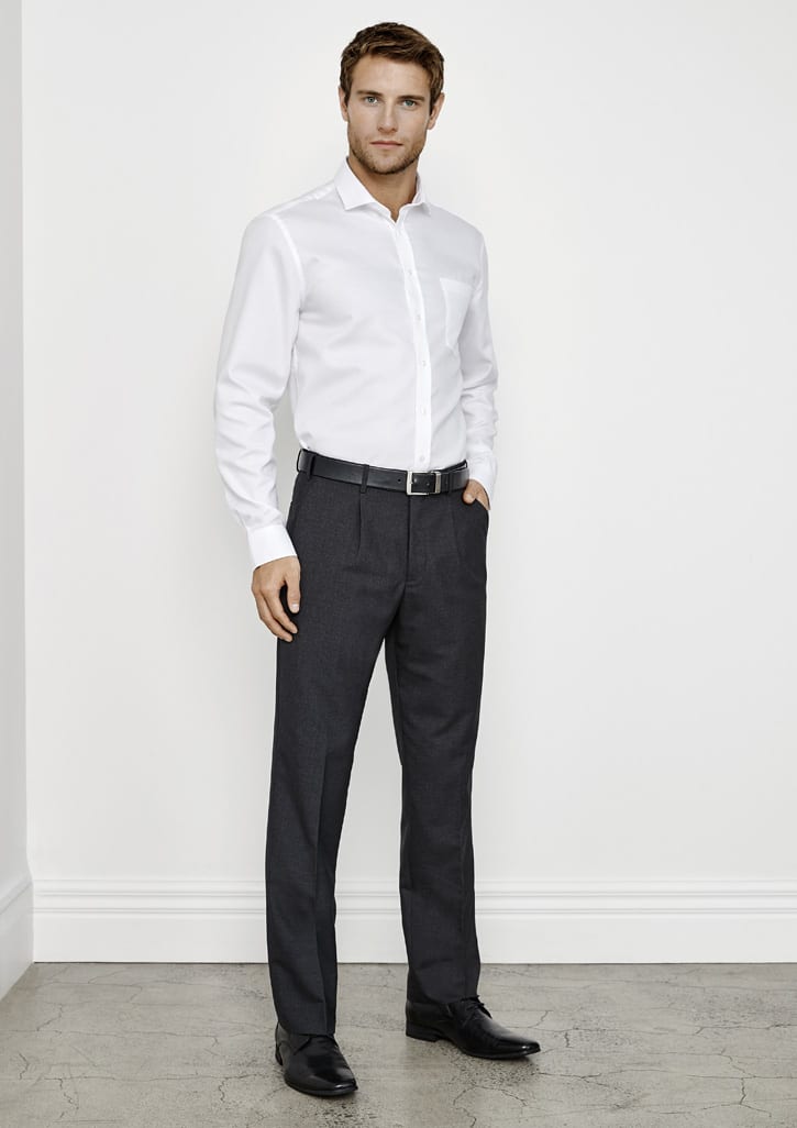 A man wearing a white shirt and dark grey classic pleat pants, standing against a plain wall backdrop.