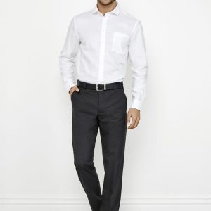 A man poses in a white shirt and dark grey classic flat pants, with a belt and sleek shoes, against a plain background.