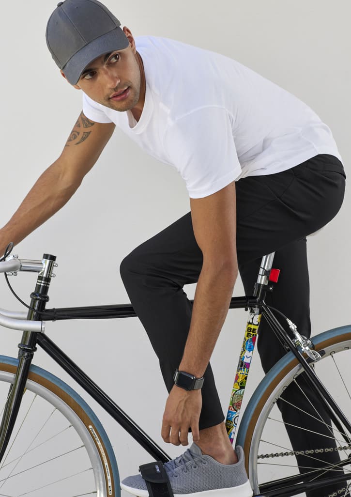 Mens Venture Pant in black, worn by a man on a bicycle, styled with a white t-shirt and grey shoes. Features a logo.