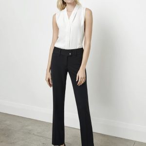A woman stands in black slacks paired with a white sleeveless top, posed against a neutral background.