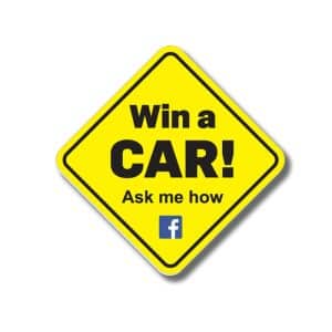 A yellow diamond-shaped sign featuring bold black lettering and a logo, advertising a car giveaway.
