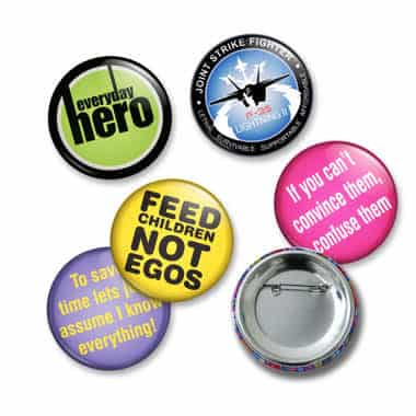 A collection of button badges in various colours, featuring different designs and shapes, including a logo on one badge.