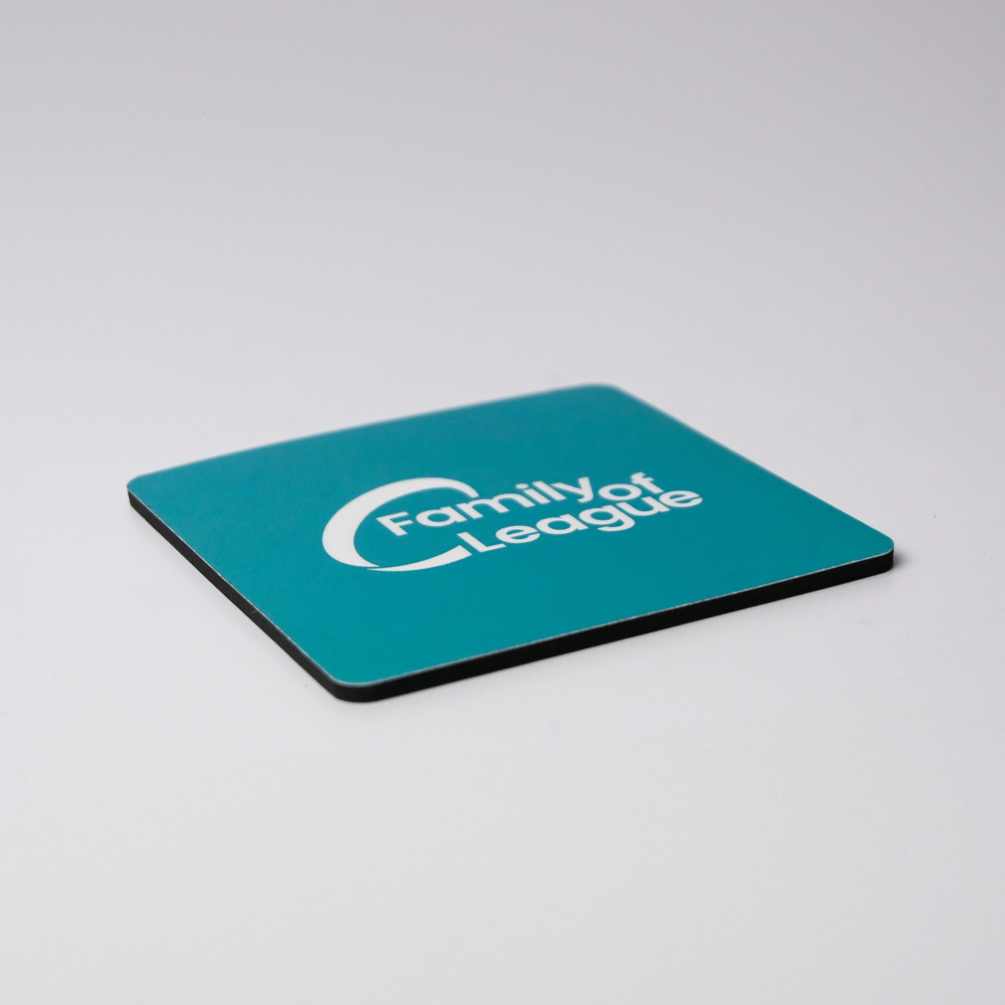 A teal coaster with a black edge features a logo on its surface.