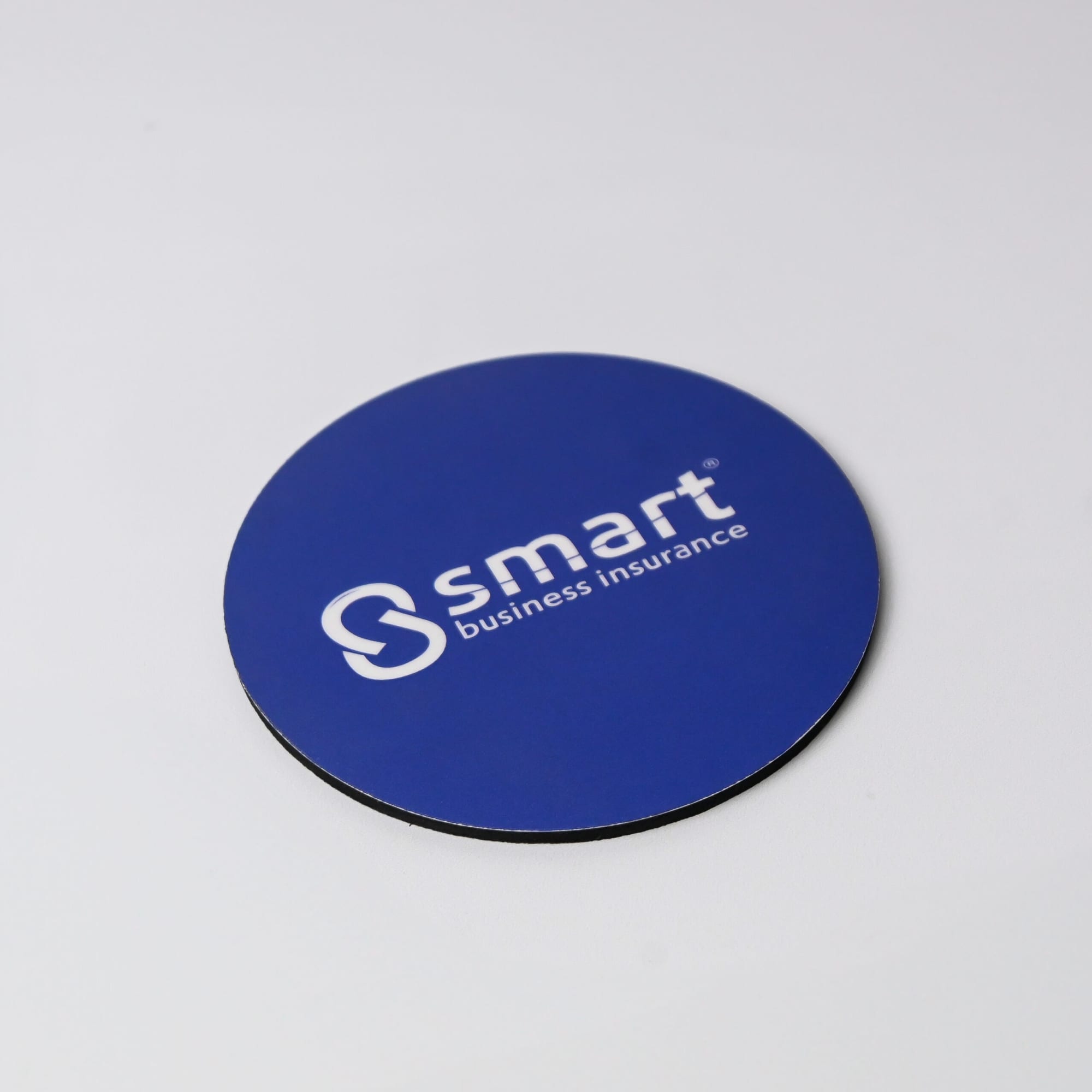 A round, blue coaster with a black underside and a white branding logo.