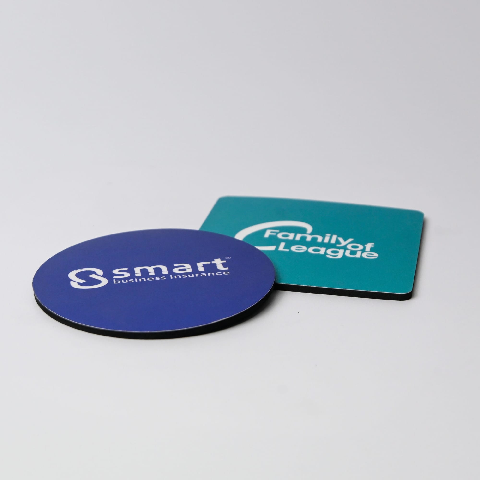 A blue circular coaster and a square black coaster, each featuring different logos, both Australian made.