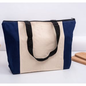 A tote bag featuring a navy blue and cream design, with black handles and a zip closure.