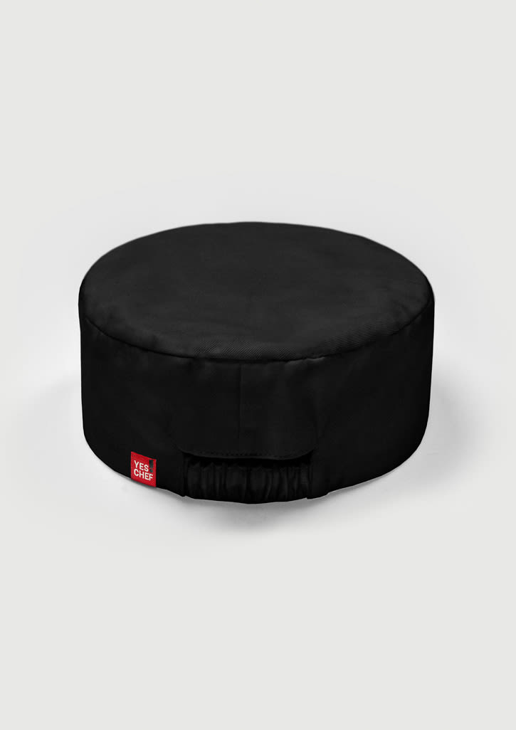 A round, black chef cap with a gathered elastic section and a small branded label.