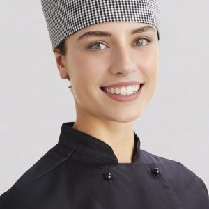 A chef cap in a black and white checkered pattern, worn by a smiling individual in a black chef's uniform.
