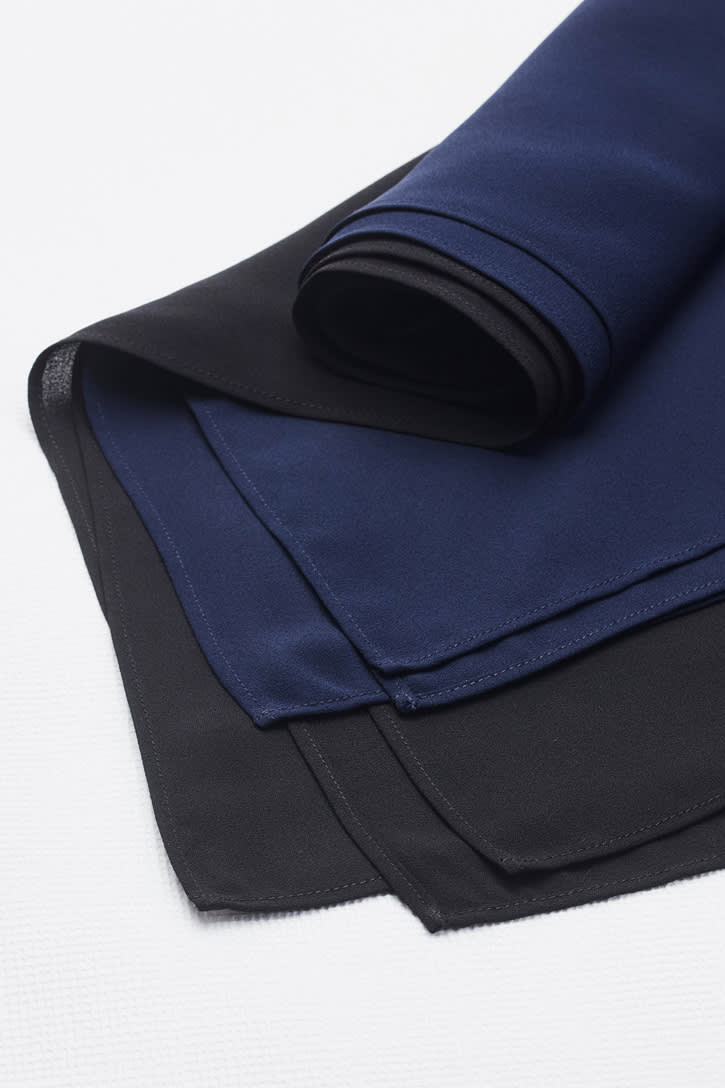 A folded women's hijab featuring layers in navy blue and black, showcasing a smooth fabric texture.