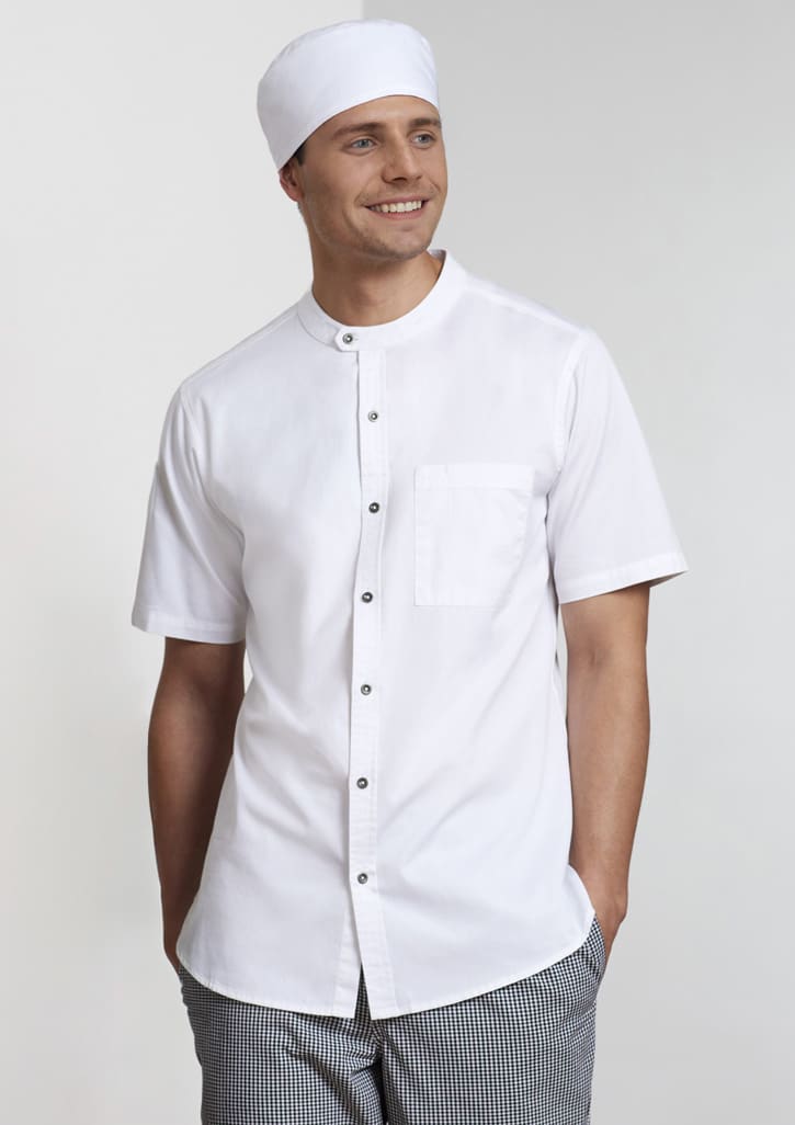 A white short sleeve chef shirt with a pocket, styled with a matching chef hat and checkered pants.