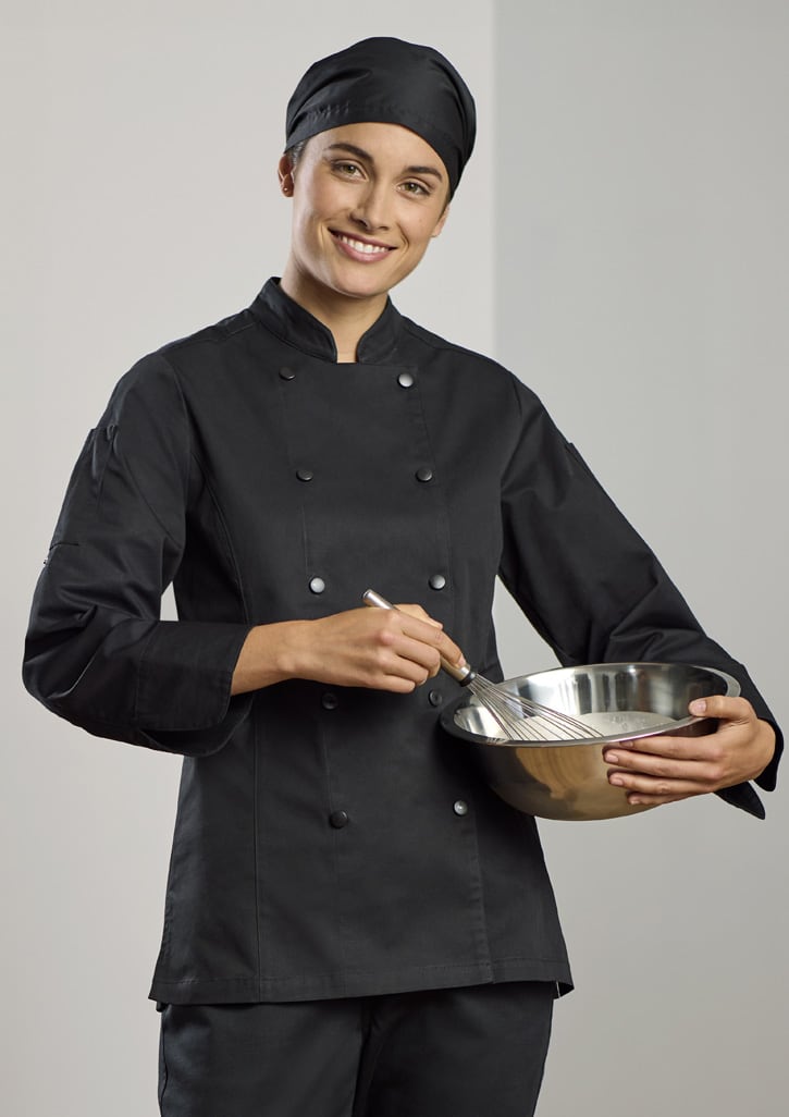 A black long sleeve chef jacket worn by a woman, who is holding a mixing bowl and whisk. The outfit includes a chef's hat.