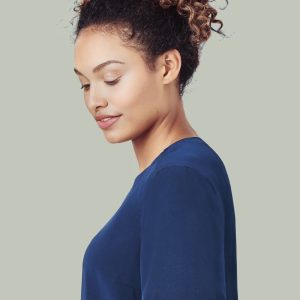A navy scrub top with a burgundy accent on the sleeve, worn by a woman with curly hair.