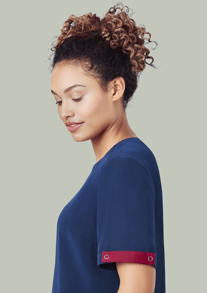 A navy scrub top with a burgundy accent on the sleeve, worn by a woman with curly hair.