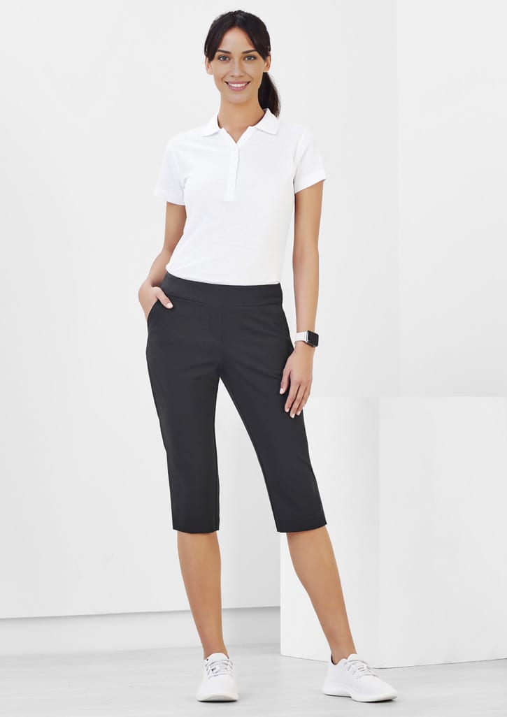 3/4 length stretch pants in black worn by a woman, featuring pockets and a sleek design. Model stands against a plain background.